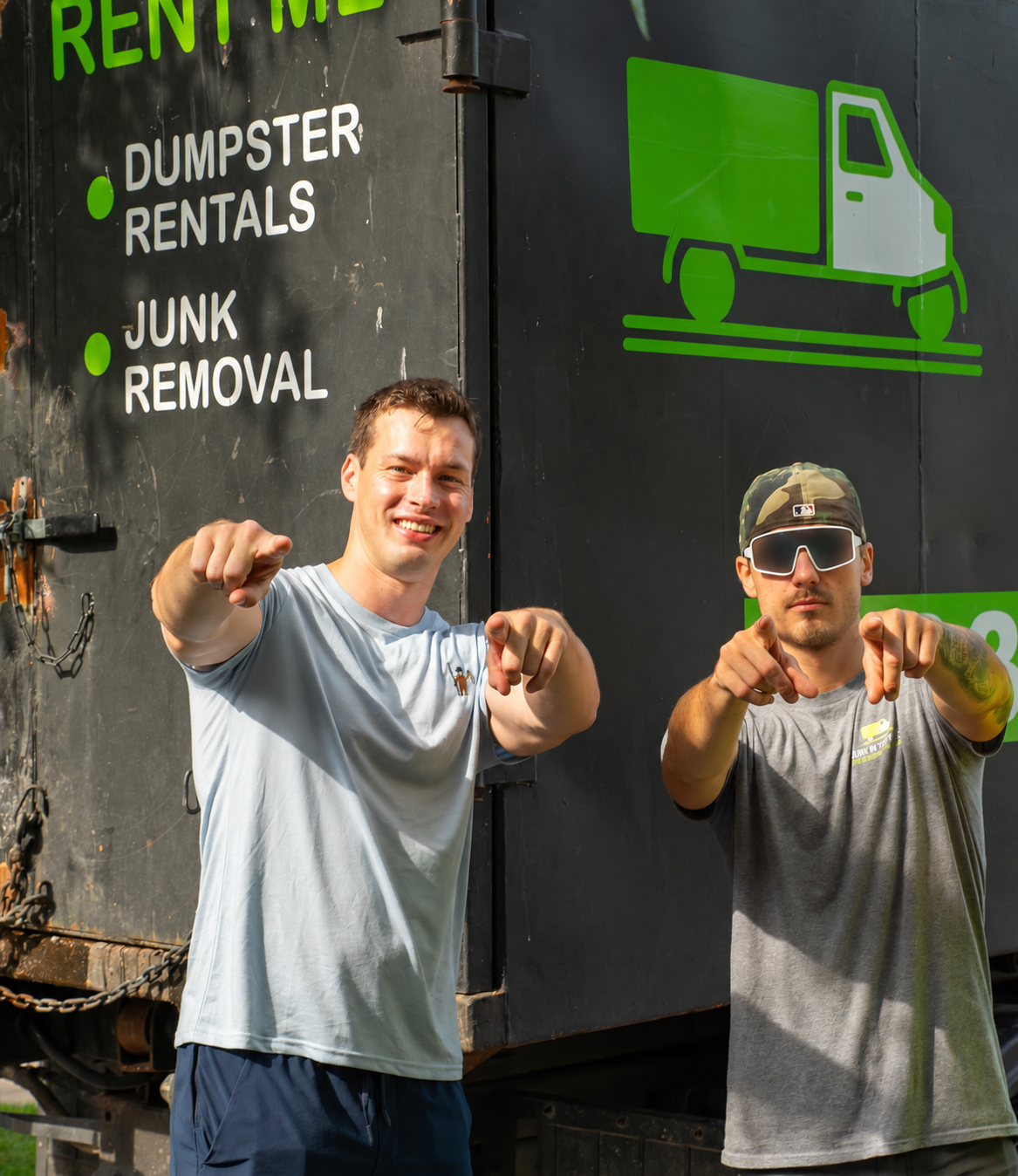 Adam with a teammate in front of a Junk in the Truck dumpster
